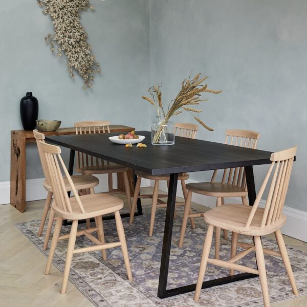 A dining room table with six chairs and a vase on the floor.
