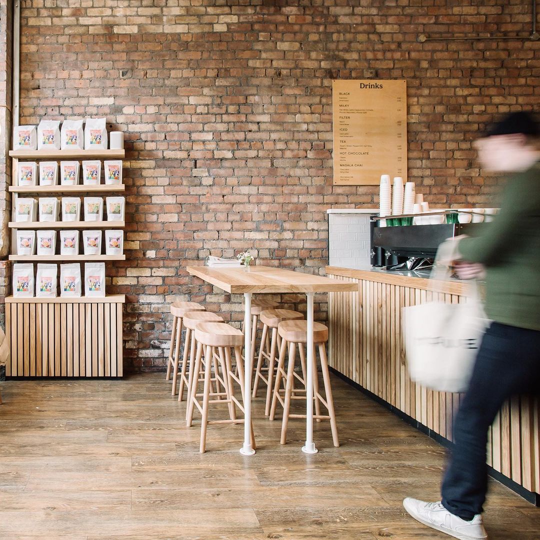 A person walking in front of a counter with stools.