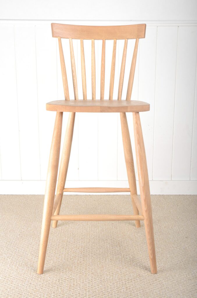 A wooden chair sitting in front of a white wall.