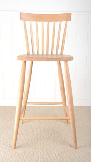 A wooden chair sitting in front of a white wall.