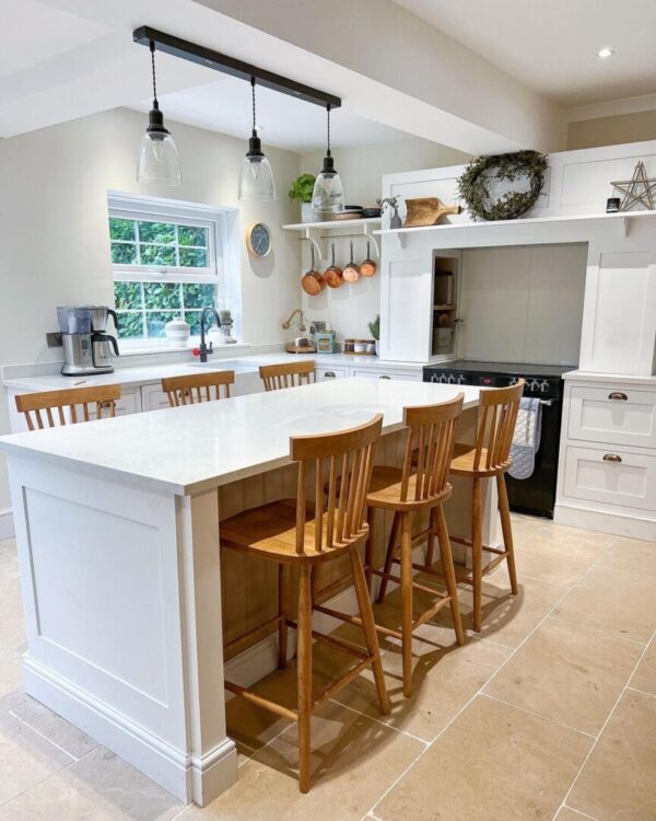 A kitchen with white cabinets and wooden chairs.