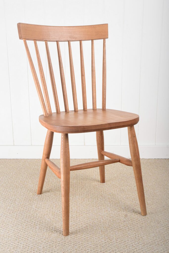A wooden chair with a long back and curved seat.