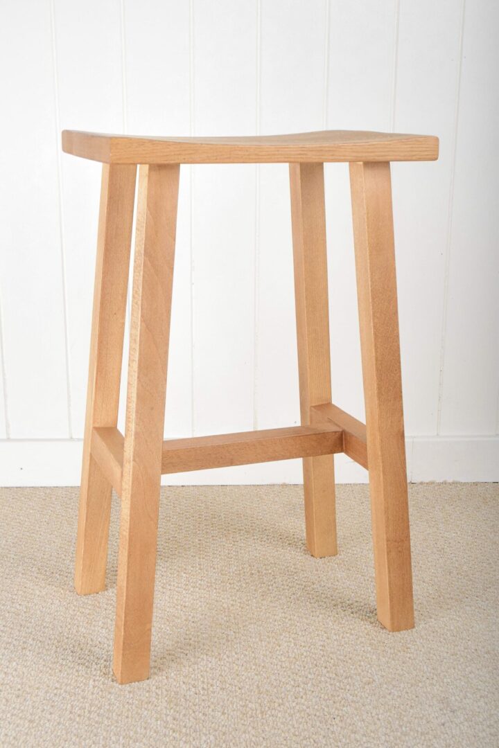 A wooden stool sitting on top of the floor.