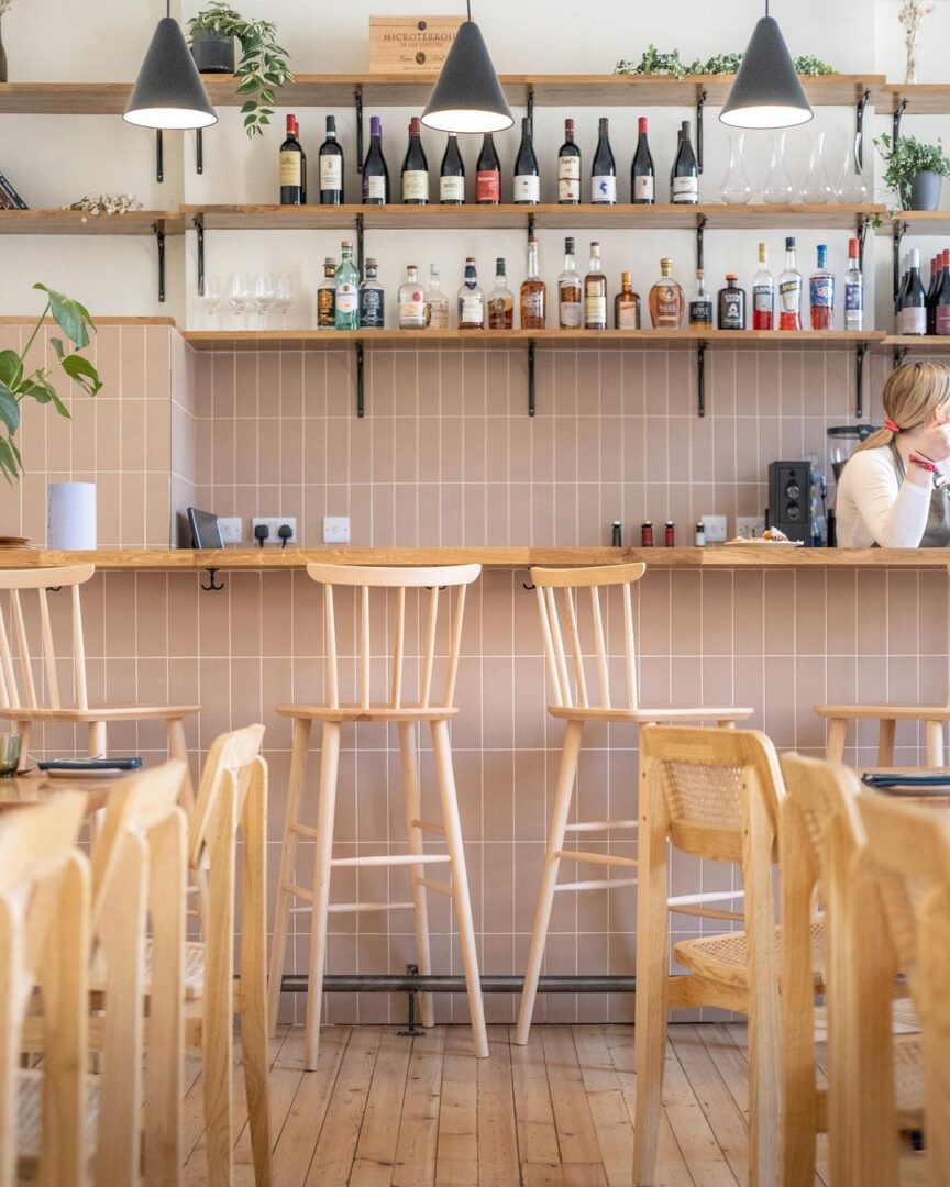 A restaurant with wooden chairs and tables in front of the bar.