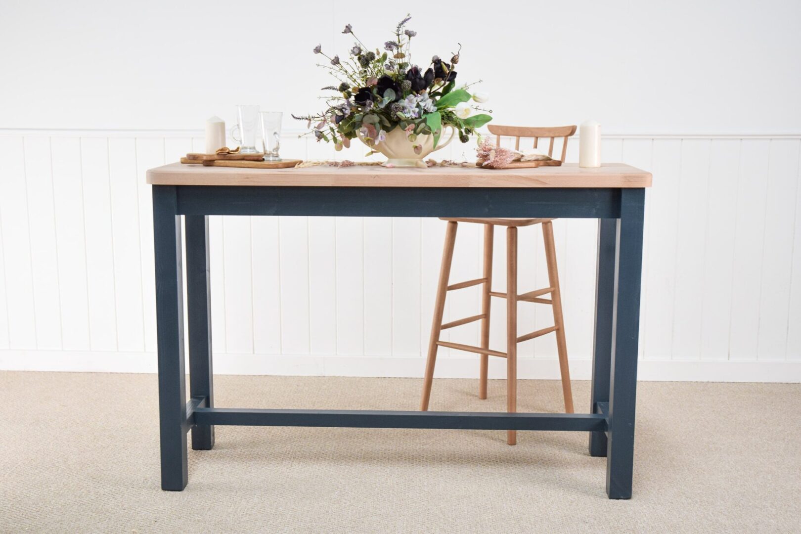 A table with two chairs and a vase of flowers on top.