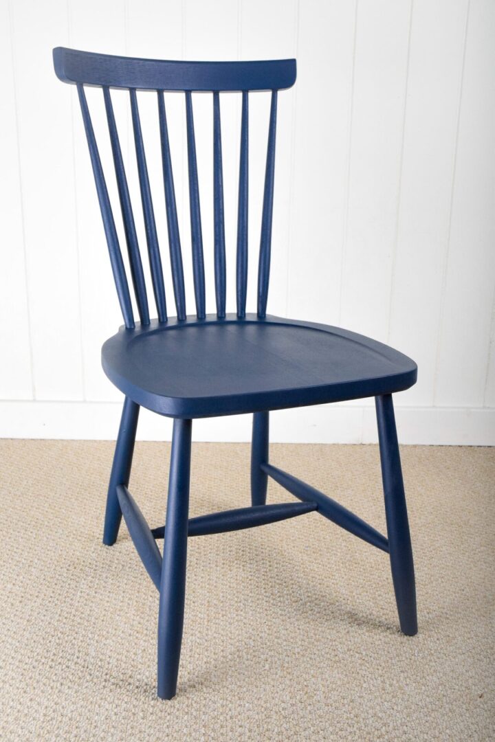 A blue chair sitting in front of a white wall.