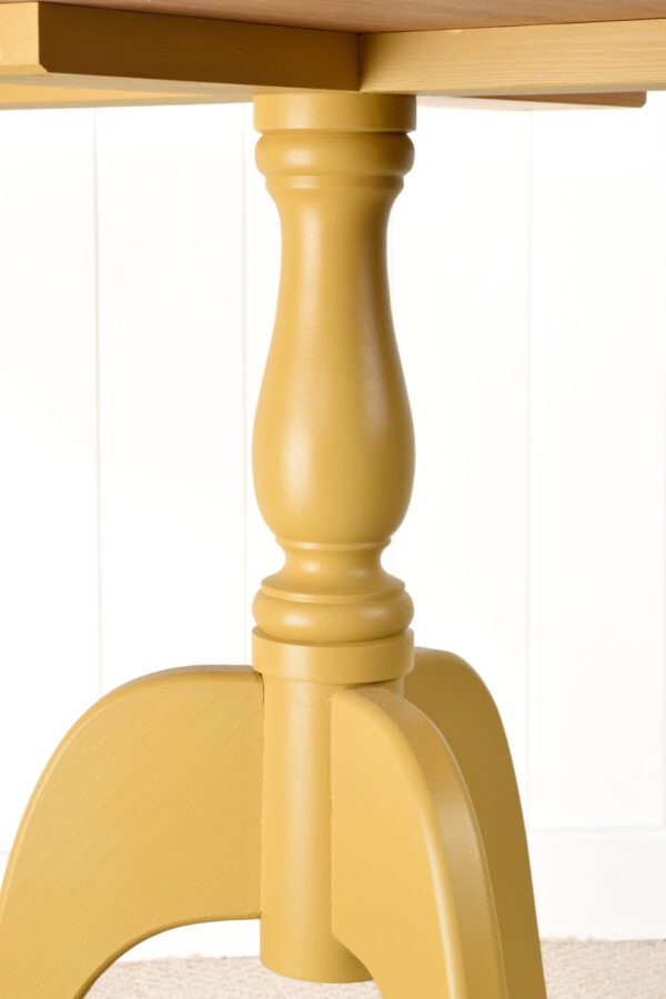 A yellow wooden object sitting on top of a table.