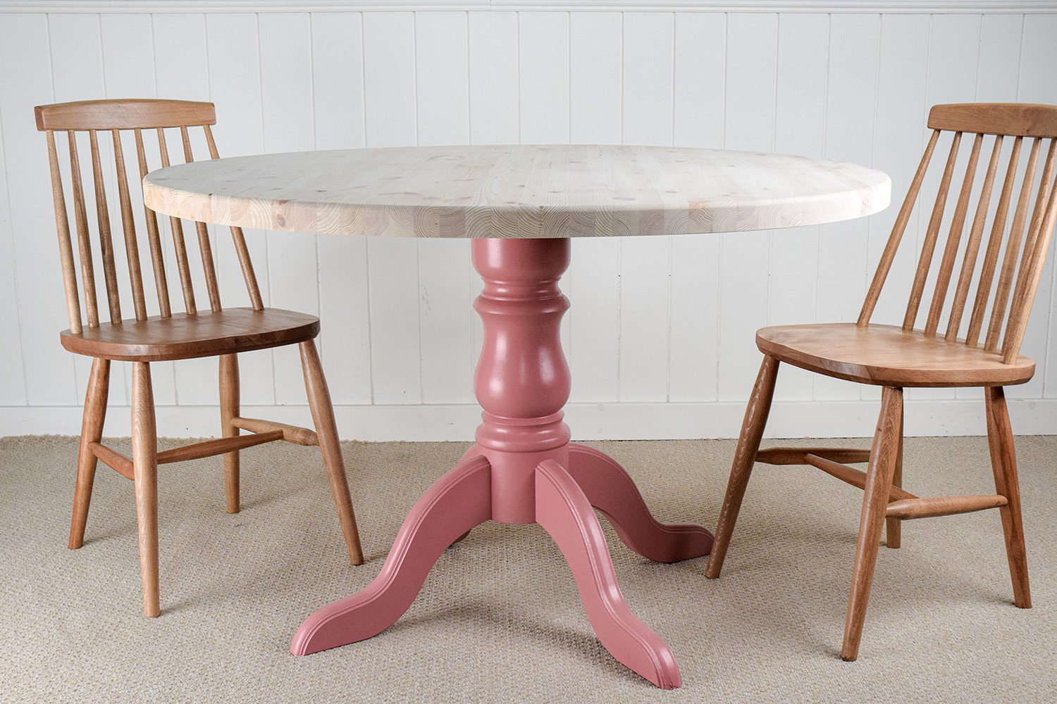 A pink table and chairs in front of a white wall.