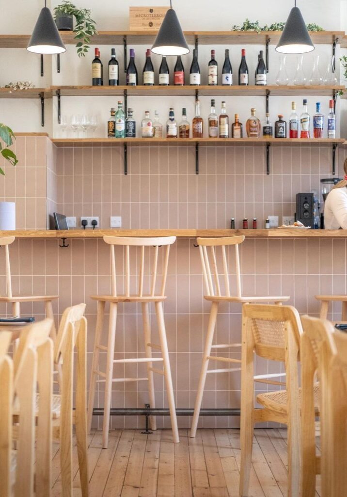 A restaurant with wooden chairs and tables in front of the bar.